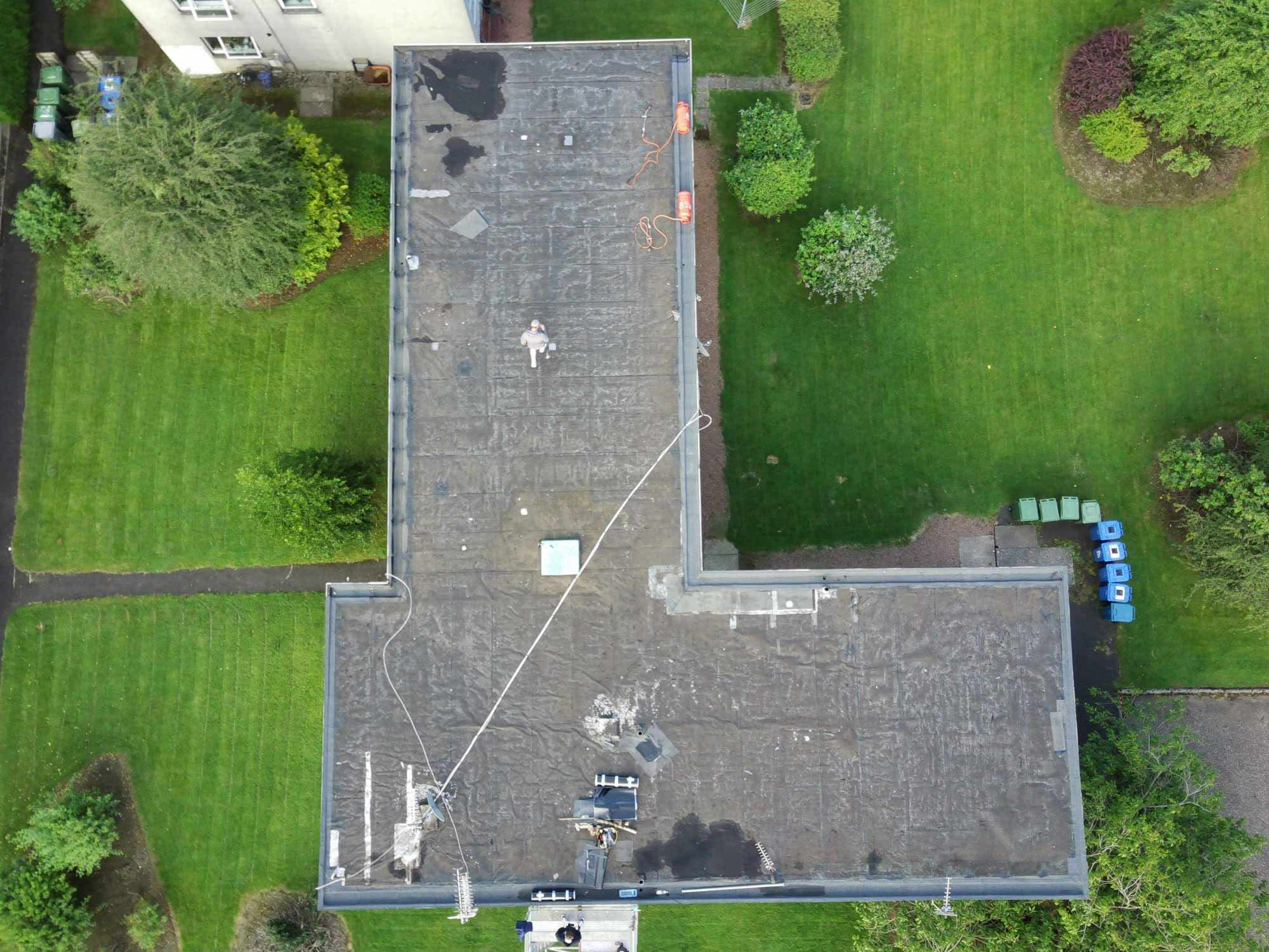 Aerial view of a large L-shaped flat roof mid-installation